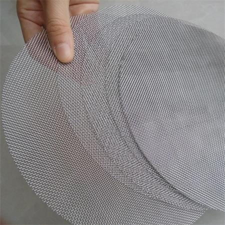 A hand is hold several pcs of wire mesh filter discs.